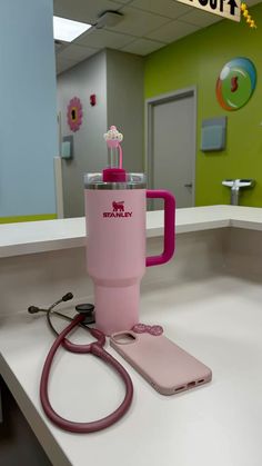 a pink coffee cup with a stethoscope on the counter next to it