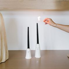 two black and white toothbrush holders on a wooden table with a hand reaching for one