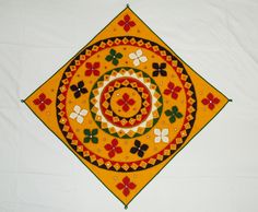 an orange and green decorative piece on a white tablecloth with flowers in the center