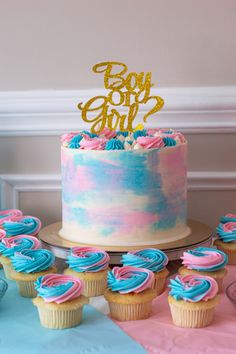 a cake and cupcakes on a table with pink, blue and gold decorations