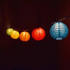 multicolored paper lanterns hanging from string in dark room