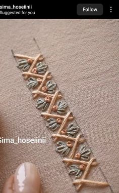 someone is stitching something on a piece of fabric with their finger and thumbnails