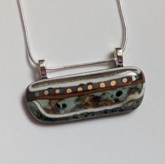 This very unique horizontal pendant was made by combining colors of glass that react with one another to form new colors. It has been embellished with white gold stripes and dots. It really looks like it could have been worn by a member of an ancient civilization! Definitely one of a kind! It has two silver-plated bails and comes with a 16-inch (extends to 18 inches) snake chain with a lobster claw clasp. I make every fused glass item by hand in my home studio. Making fused glass jewelry involve Glass Infused Jewelry, Combining Colors, Ancient Civilization, Fused Glass Pendant, Fused Glass Jewelry, Gold Stripes, Artistic Jewelry, Glass Earrings, Snake Chain