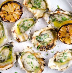 several oysters on a plate with lemon wedges