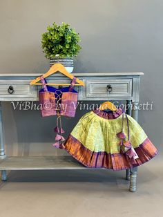 Indulge in luxury with our Mint and Purple Kanchi Silk Skirt And Top. Crafted with copper zari and handcrafted tassels, this set exudes elegance and comfort. The sleeveless dori back adds a touch of uniqueness, making it perfect for any occasion. Soft, comfortable, and adorable, it's a must-have for your little girl's wardrobe. Silk Skirt And Top, Mint And Purple, Purple Color Combinations, Fancy Clutch, Kids Wear Boys, Pleated Saree, Kids Wear Girls, Bangle Box, Block Print Saree