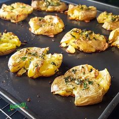 baked potatoes with herbs and seasoning sitting on a baking sheet