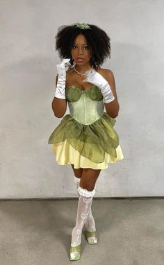 a woman in a green and yellow dress with white gloves on her head is posing for the camera