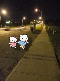 an image of two hello kitty stickers on the side of a road at night