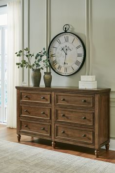 a large clock mounted to the side of a wooden dresser