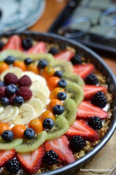 a fruit salad with bananas, kiwis, strawberries and oranges on top