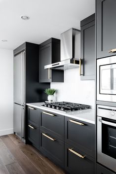 a black and white kitchen with gold trimmings on the oven, stove top and cabinets