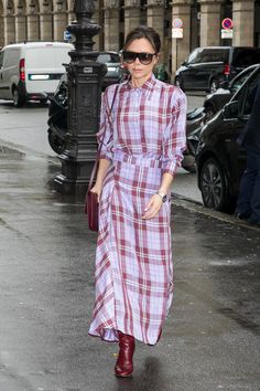 a woman walking down the street wearing a plaid shirt dress and red ankle high boots