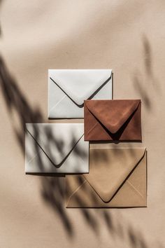 four envelopes are lined up on top of each other in different colors and shapes