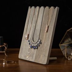 a wooden stand holding several necklaces on top of a table next to other jewelry