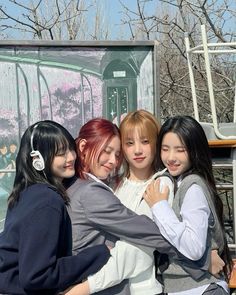 four girls are hugging each other in front of a painting