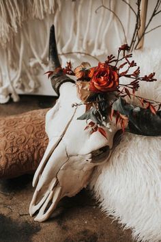 an animal skull with flowers on it's head sitting on a rug next to a wall