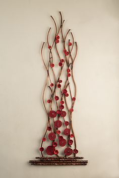 a metal wall sculpture with red flowers on it