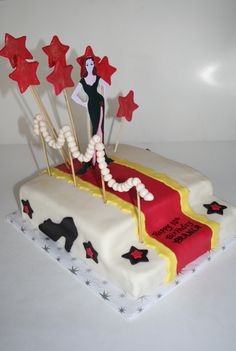 a cake decorated with red and white icing, stars and a woman on top