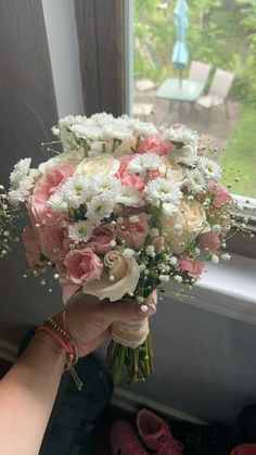 a person holding a bouquet of flowers in front of a window