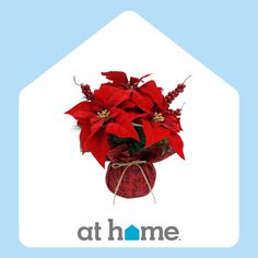 a vase filled with red flowers on top of a blue and white sign that says at home