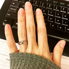 a person's hand with two rings on their fingers next to a keyboard