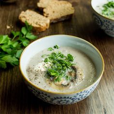 a bowl of soup with bread and parsley on the side