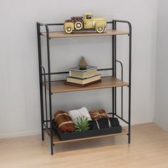 three tiered shelf with books and toy cars on top, in front of a white wall