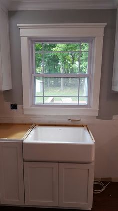 an empty kitchen with white cabinets and a window above the sink that has no curtains on it