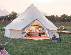 a large tent set up in the middle of a field with chairs and tables around it