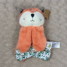 an orange teddy bear with green leaves on it's leg and its eyes closed