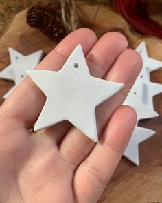 a hand holding a white star ornament on top of a wooden table