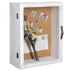 a white frame with flowers and post it notes on the cork notice board in it