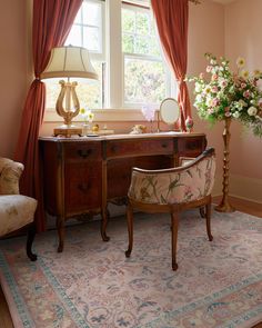 a room with a desk, chair and flowers on the rug in front of it