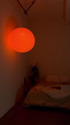 an orange lamp hanging over a bed in a room