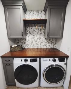 a washer and dryer in a small room with wooden counter tops on each side