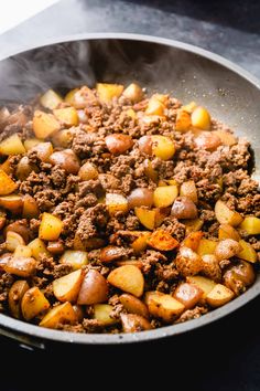 a pan filled with meat and potatoes on top of a stove