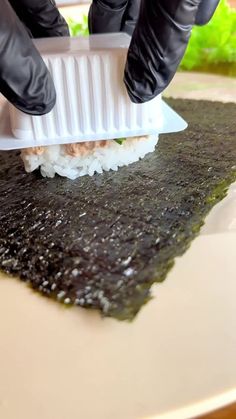 a person in black gloves is cutting sushi