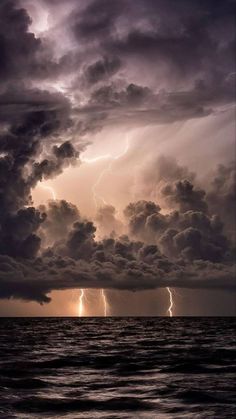 the sky is filled with dark clouds and lightning bolting over the ocean in front of it