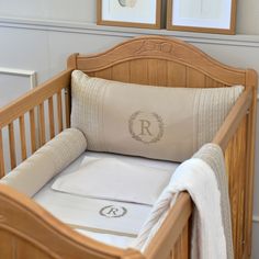 a baby crib with two framed pictures on the wall behind it and a monogrammed pillow