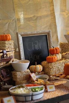 a table topped with hay bales filled with different types of foods and vegetables next to a chalkboard sign