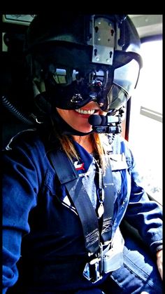 a woman sitting in the cockpit of an airplane wearing a pilot's helmet and goggles