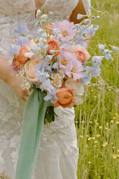 a bride holding a bouquet of flowers in her hands and wearing a wedding dress with an aqua sash