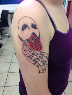 a woman with a tattoo on her arm holding a rose in front of her face