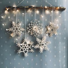 snowflakes are hanging on a wall with string lights