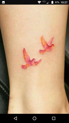 two birds on the side of a woman's foot with pink and orange colors