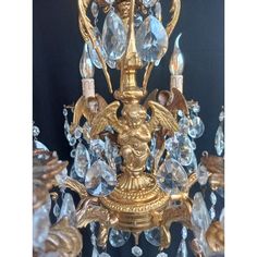 a gold chandelier with crystal drops hanging from it's sides and an eagle figurine on top