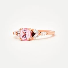 Custom designed by Amelie, and exclusive to Identity Diamonds Recycled metal Set in the center with a lovely 1.25ct* (6mm) cushion cut lab-grown rosé sapphire With a blush hue reminiscent of the color of morganite, our rosé sapphire features a slightly more saturated pink, and it offers a much better durability than morganite, making it ideal for an engagement ring! Available in two different tones: a hint of peach, or a hint of lavender in it Features six marquise shaped lab-grown diamonds, for Rose Gold Cushion Cut Morganite Ring, Rose Gold Cushion Cut Ring With Accent Stones, Luxury Rose Gold Square Cut Ring, Rose Gold Square Cut Wedding Rings, 14k Rose Gold Asscher Cut Ring, Rose Gold Asscher-cut Ring With Center Stone, Rose Gold Asscher Cut Ring With Center Stone, Rose Gold Square Cut Promise Ring, Rose Gold Rings With Asscher Cut Center Stone