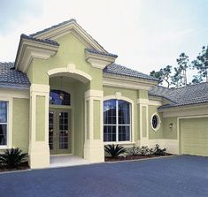 a yellow house with two garages and three windows on the front side of it