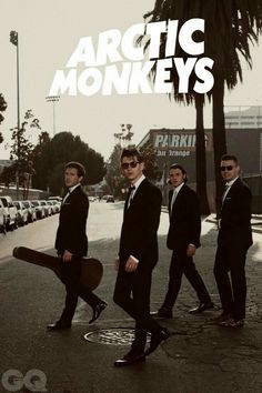 the arctic monkeys are walking down the street with their skateboards in hand and there is an advertisement above them that says arctic monkeys