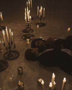 a person laying on the ground surrounded by candles